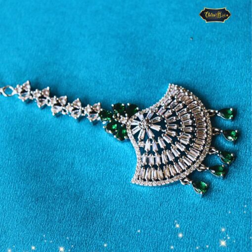Emerald Radiance Maang Tikka with gold detailing and emerald centerpiece, designed as elegant forehead jewelry for weddings and traditional Indian occasions.