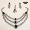 Triple-layered emerald green teardrop CZ bridal jewelry set featuring a necklace, jhumka-style earrings, and maang tikka