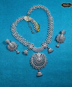 Silver Indian bridal jewelry set featuring floral necklace and matching bell-design earrings, displayed on traditional bridal attire.
