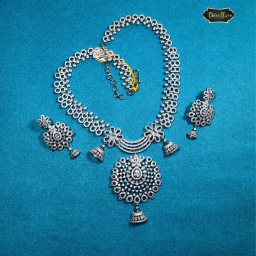 Silver Indian bridal jewelry set featuring floral necklace and matching bell-design earrings, displayed on traditional bridal attire.